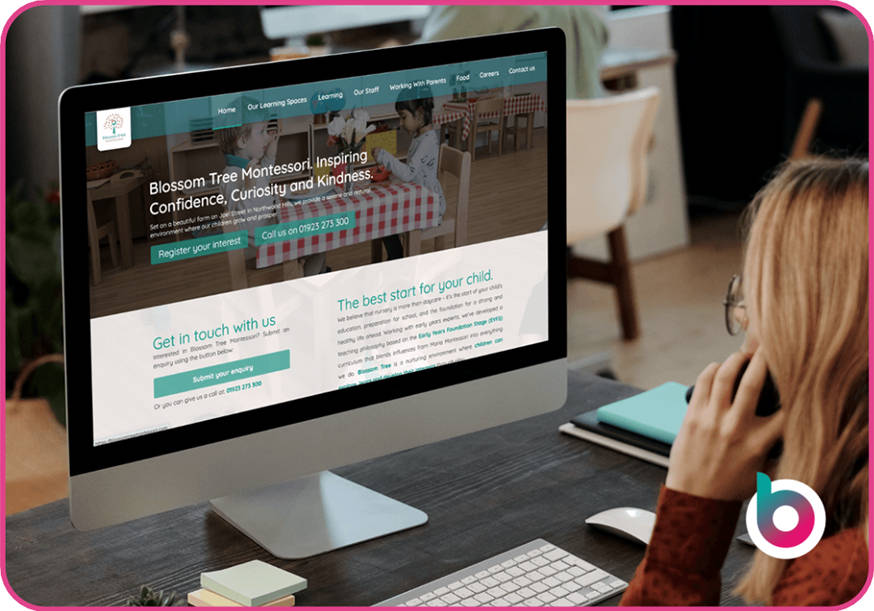 A-woman-on-a-phone-using-a-computer-with-a-nursery-website-on-the-screen-like-Be-Seen