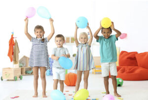 Four children stand in a line holding balloons