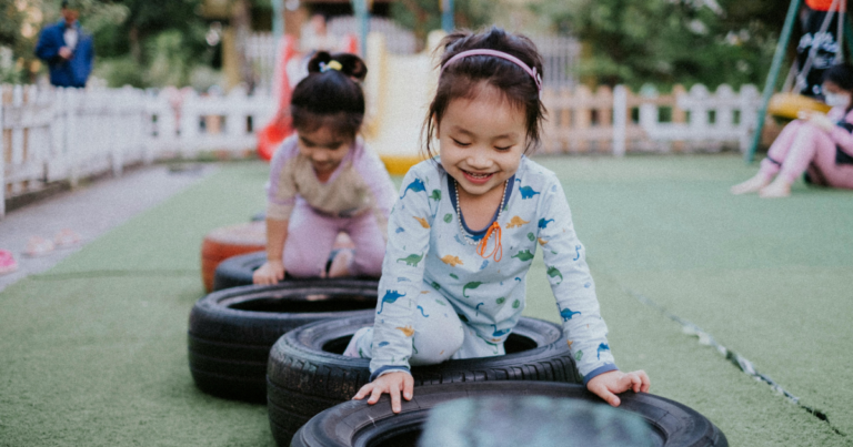 Two girls playing in old tyres