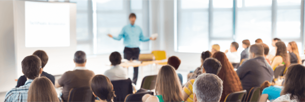 Someone giving a presentation or speech in front of an audience, looking like an office-type setting
