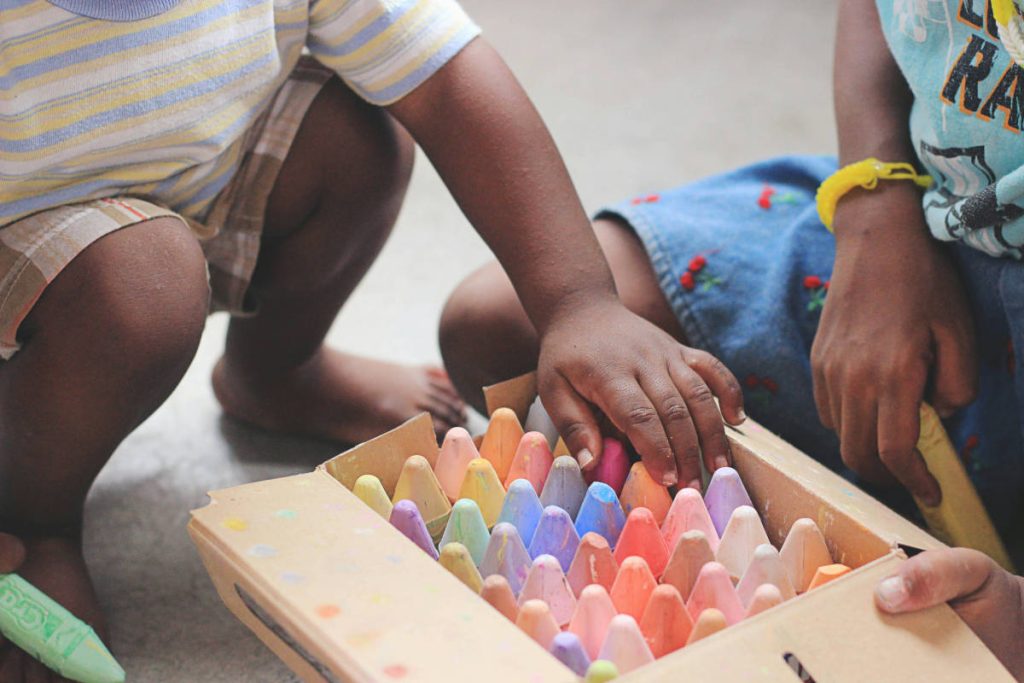 Sensory-play-header-image-Children-playing-with-chalky-crayons-in-a-box-1200