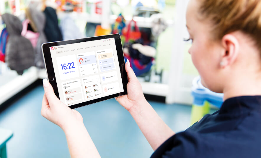 A woman holding a tablet in a nursery setting with Ovivio Workspace on the screen