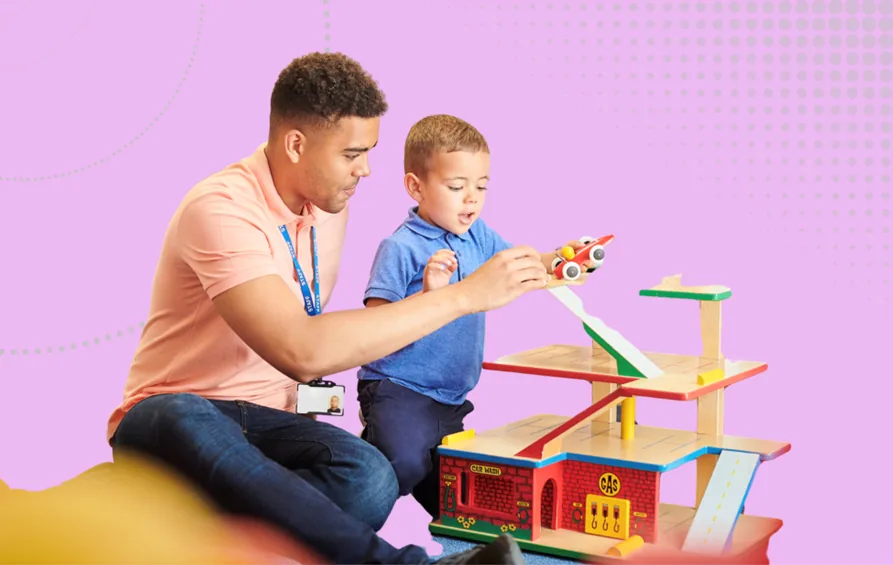 Nursery leadership and governance Image - A male childcare worker playing with a young child at a wooden tower