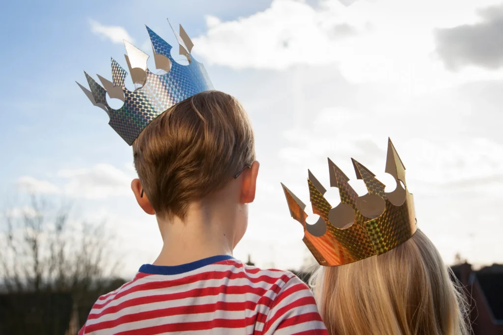 Twee kinderen met een papieren kroon kijken omhoog naar de lucht, beeld bij de kinderopvangtoeslag 2027